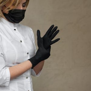 Professional wearing black nitrile gloves, showcasing the sleek design and reliability of the gloves in various industries such as healthcare, food service, cleaning, and more.